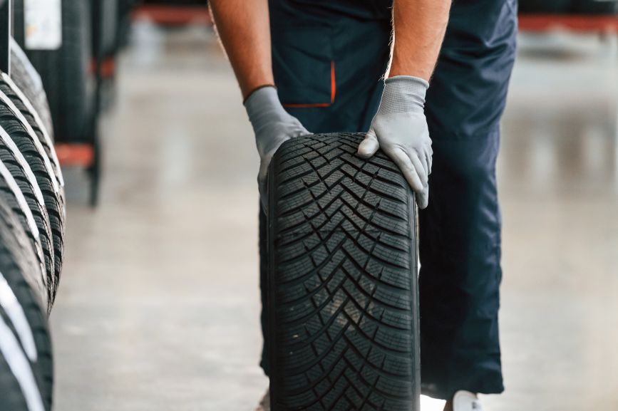 a mechanic inspecting the deep tread pattern of a new car tyre in a workshop