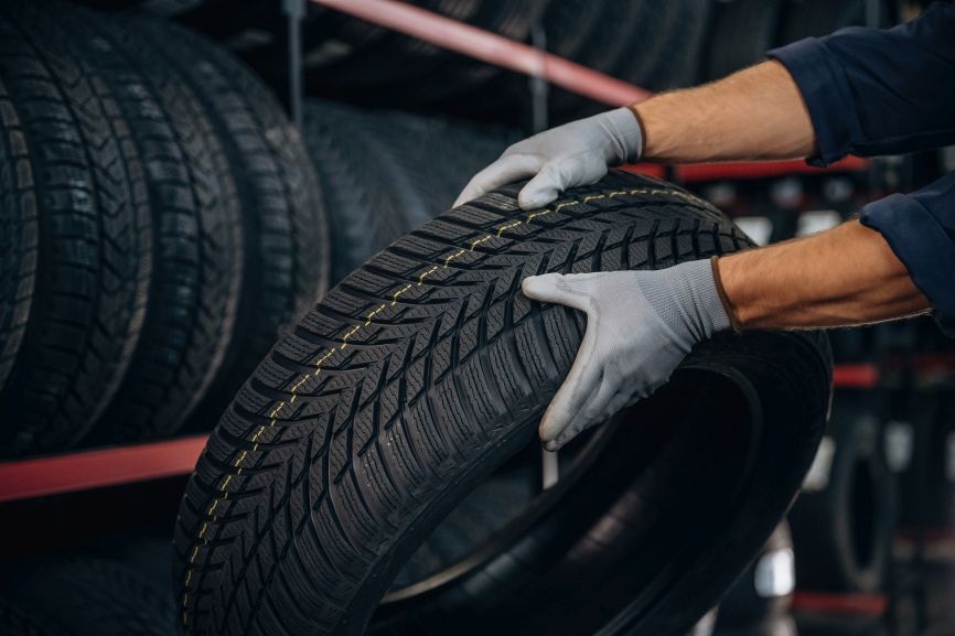 a mechanic inspecting the tread pattern of an affordable budget brand car tyre