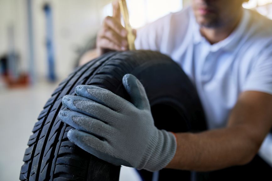mechanic checking tyre tread depth on a car tyre