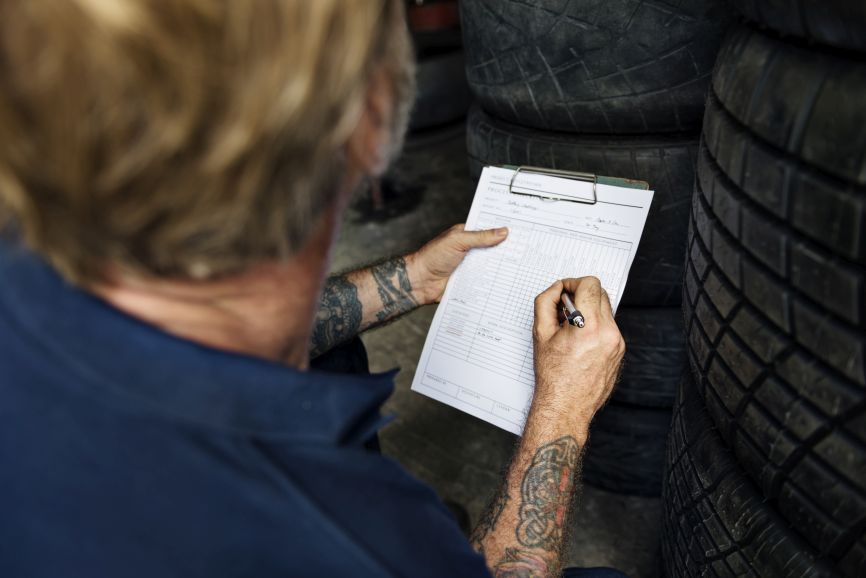 mechanic records tyre details after a car failed mot inspection
