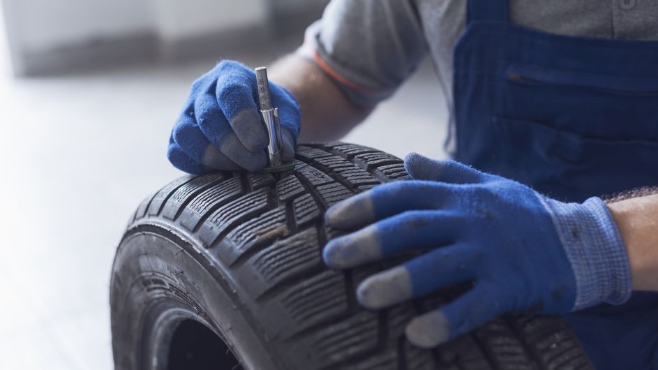 technician measuring tyre tread depth with a tread gauge